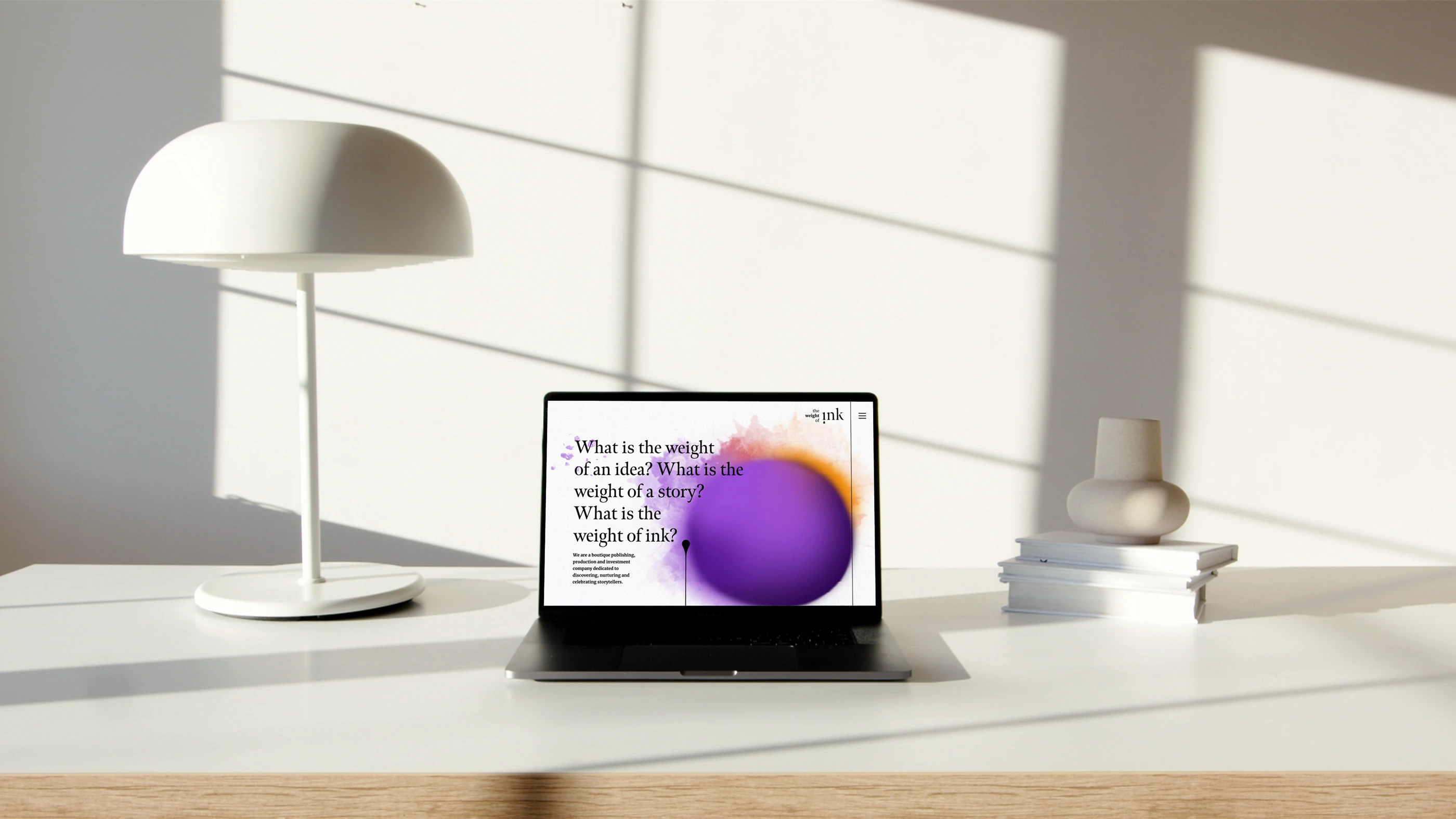 The Weight of Ink website displayed on a laptop in a sunlit interior.